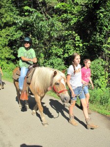 From left, Ben Merucci rides a horse led by Madison Dahlin, 14, and Halee Alexander, 12, volunteers at O.A.T.S. in Brandon Township. Photo by Susan Bromley.