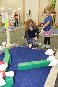 Reagan DeLisle 10 helps Evelyen Schmalts, 5, line-up her ball at the Brandon Township library. Photo by Patrick McAbee. 